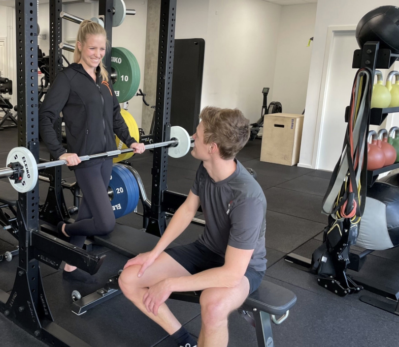 Anja vejleder klient ved squat-rack i ACTGYM-studiet.