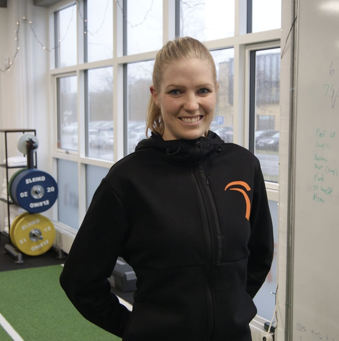 Portræt af Anja Lambek i sit eget træningsstudie ACTGYM, iført sort ACTGYM-hættetrøje.